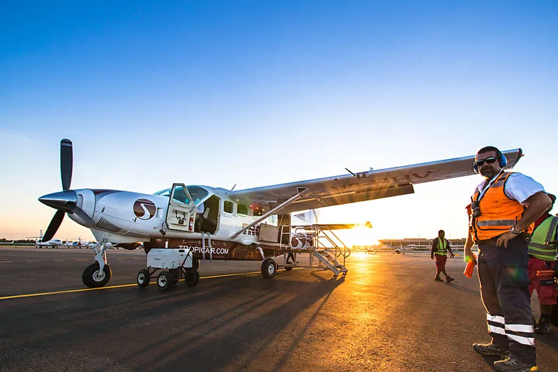 Tropic Air plane at sunrise in Belize, with a staff member standing at the wingtip.